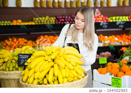 Young female choosing fresh bananas on the supermarket 104502985