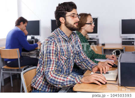 Man working with computer and books in library Man working with computer and books in library 104503393