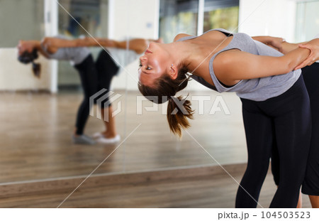 females doing stretching workout in pairs 104503523