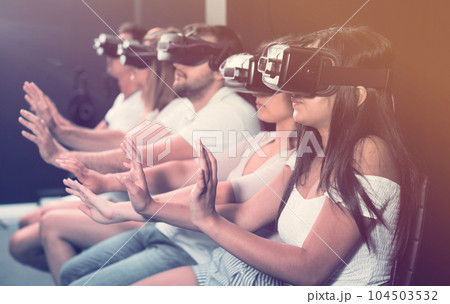 Female is enjoying exciting movie with friends in VR glasses 104503532
