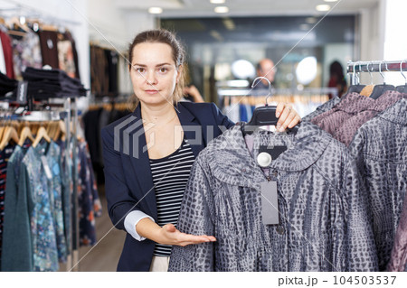 Shop assistant demonstrating coat in shop Shop assistant demonstrating coat in shop 104503537