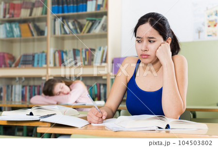 Young girl is thinking about difficult task at the desk 104503802