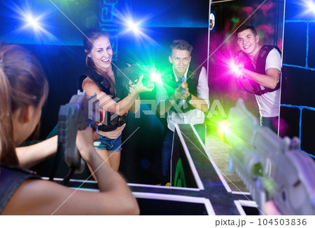 Two laser tag teams playing enthusiastically and aiming at each 104503836