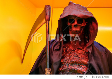 Death with a scythe. A skeleton of a man in black clothes with a place for text, copying on a yellow background Death with a scythe. A skeleton of a man in black clothes with a place for text, copying on a yellow background 104504266