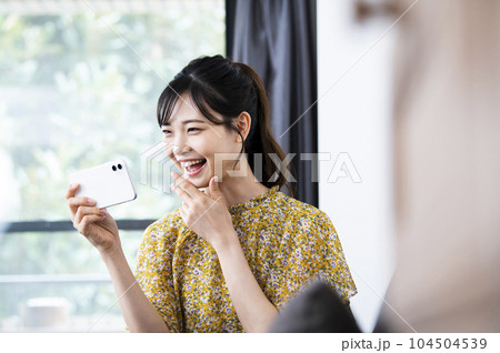 笑顔でスマホを見る若い女性 104504539