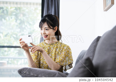 笑顔でスマホを見る若い女性 笑顔でスマホを見る若い女性 104504542