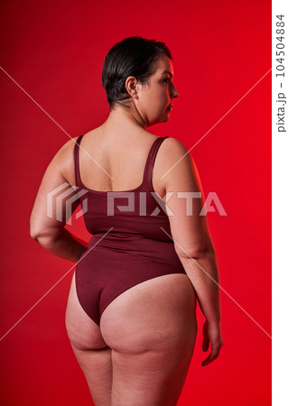 Asian woman in underwear standing over red studio background Asian woman in underwear standing over red studio background 104504884