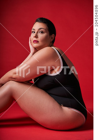 Confident body positive asian woman looking at the camera while sitting Confident body positive asian woman looking at the camera while sitting 104504896