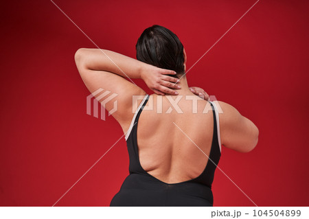 Back view of self-confident woman wearing underwear against red wall Back view of self-confident woman wearing underwear against red wall 104504899