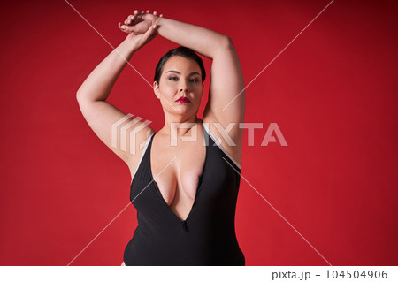 Serious body positive woman enjoying her natural body while standing Serious body positive woman enjoying her natural body while standing 104504906