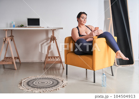 Full length view of the body positive woman sitting at the armchair 104504913