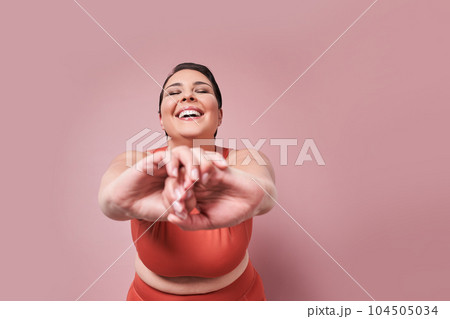 Young overweight woman stretching arms and training in sportswear 104505034