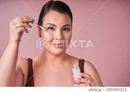 Happy body positive woman holding dropper with nourishing face serum Happy body positive woman holding dropper with nourishing face serum 104505213