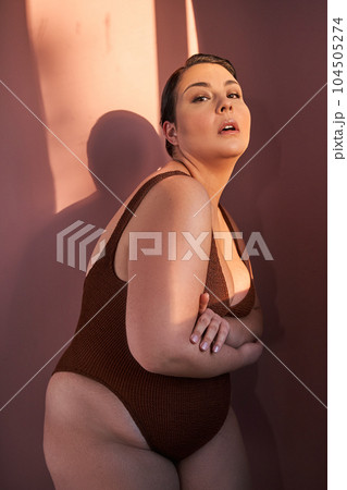 Vertical portrait of half-turned curvy woman with perfect skin looking at camera 104505274