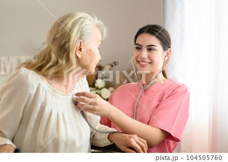 Happy doctor talking with elderly patient at home visit 104505760