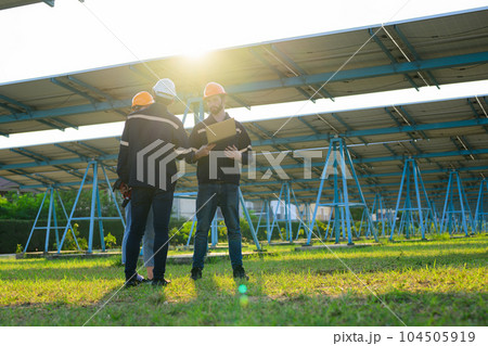 Workers installing solar panels, Engineer team at solar panel farm 104505919
