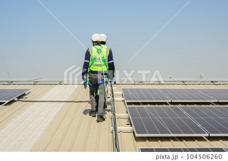 Engineers with safety helmet checking solar system at solar power farm 104506260