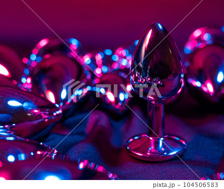 Lots of metal anal plugs in neon pink purple light.  104506583