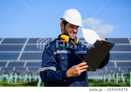 Technician worker installing solar panels at solar cell farm 104506878