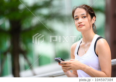 Woman enjoying and relaxing outdoor with smartphone in green park Woman enjoying and relaxing outdoor with smartphone in green park 104507384