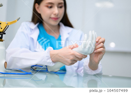 Technician testing robotic bionic arm at prosthetic manufacturing Technician testing robotic bionic arm at prosthetic manufacturing 104507499