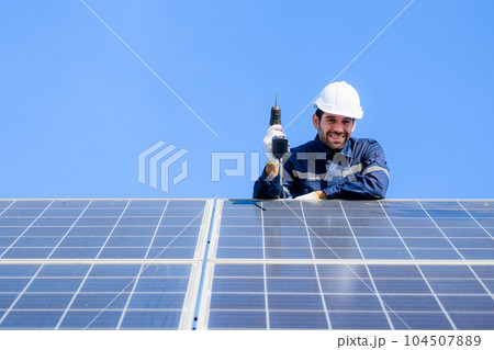 Technician worker installing solar panels at solar cell farm 104507889