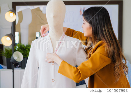 Female fashion designer woman working on her designs in workshop studio, Female business owner with clothes, Tailoring business owner, Clothing store owner, Design fashion clothes by designer Female fashion designer woman working on her designs in workshop studio, Female business owner with clothes, Tailoring business owner, Clothing store owner, Design fashion clothes by designer 104507998