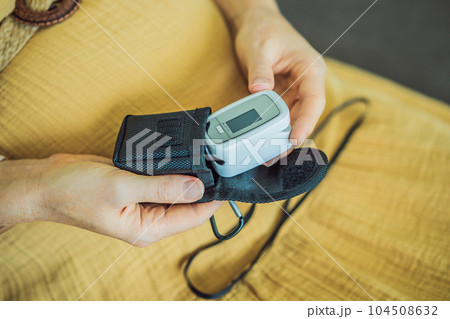 Pregnant woman with pulse oximeter on finger. Doctor measuring oxygen saturation level while visiting expectant mother with coronavirus disease at home, cropped. Pregnancy and covid-19 concept 104508632