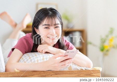 リビングでスマホを見る若い女性 104509222