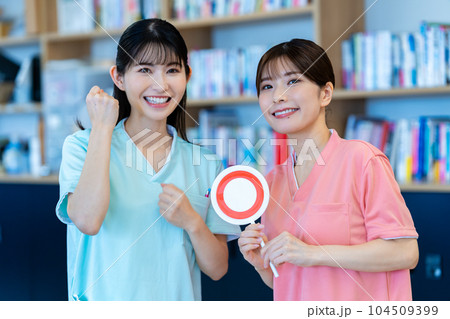 OKのプレートを出す二人の看護師の女性 104509399