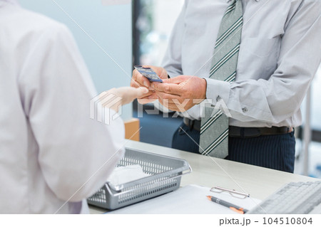 薬局で薬剤師・調剤師に相談する高齢者・中高年男性（服薬指導） 104510804