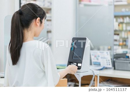 薬局・病院でマイナンバーカードをカードリーダーの機械で読み込む女性 薬局・病院でマイナンバーカードをカードリーダーの機械で読み込む女性 104511137