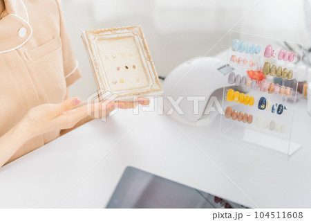 ネイルサロンで見本を見せてオプションのデザインを相談するネイリストとアジア人女性 104511608