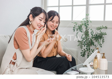 友達と一緒にメイク・身支度をする笑顔のアジア人女性 友達と一緒にメイク・身支度をする笑顔のアジア人女性 104513573