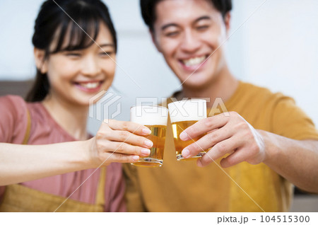 ビールで乾杯する若い夫婦 手元ピント ビールで乾杯する若い夫婦 手元ピント 104515300