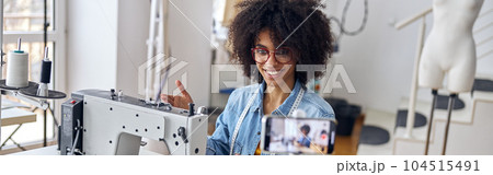 African-American lady shows contemporary sewing machine shooting new video in workshop 104515491