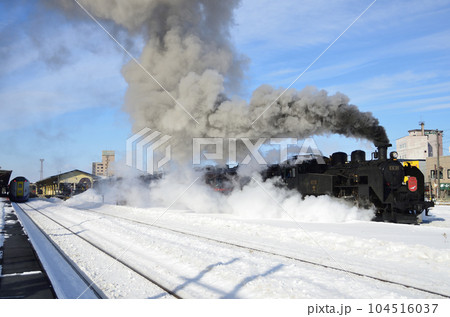 ドレン弁から出る蒸気に包まれながら釧路駅を出発する「SL冬の湿原号」 104516037