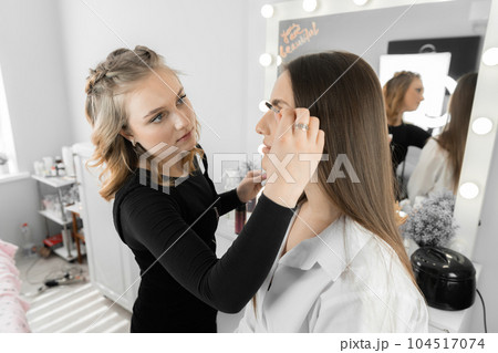 The process of eyebrow correction in the beauty salon. Master carefully applies each brush with great attention, creating individual design that gives a woman's face a special appeal in beauty salon 104517074