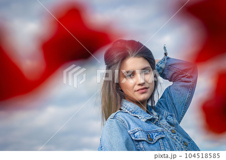 Portrait of  attractive long haired girl from behind red poppy leaves. 104518585