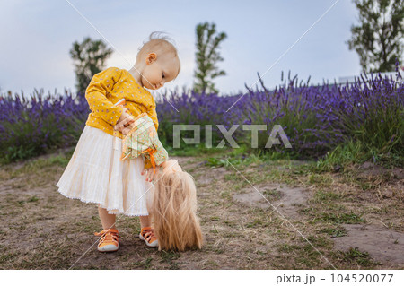 little girl holding a doll on the background of a lavender field 104520077