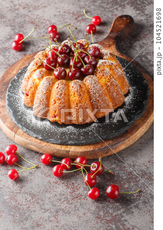 Tasty baked cherry bundt cake close-up on a wooden board. Vertical 104521698