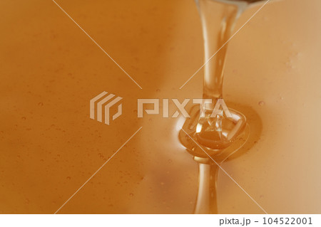 Closeup shot of organic honey pouring in bowl Closeup shot of organic honey pouring in bowl 104522001