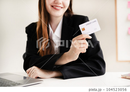 Asian girl shopping online holding credit and using laptop enter their card number in the mobile phone app to purchase and payment in internet store Asian girl shopping online holding credit and using laptop enter their card number in the mobile phone app to purchase and payment in internet store 104523056