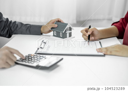 A real estate agent with a home model is talking to clients about renting a house and buying home insurance and contracting the contract after the formal negotiation is completed 104523289