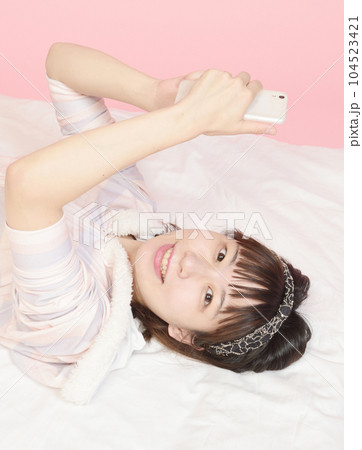 パジャマ姿でスマホを操作する女性 パジャマ姿でスマホを操作する女性 104523421