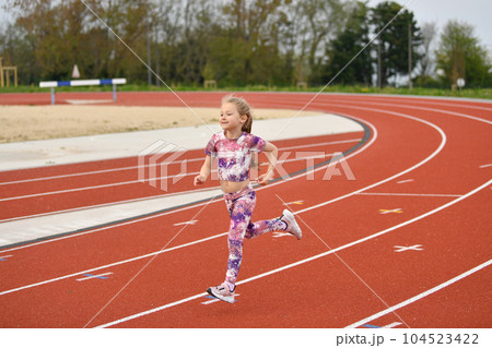 A girl in pink sneakers runs in the stadium 104523422