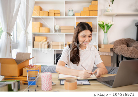 Woman Writing Customer Details for Shipping in Home Office, Packing Box and Writing Customer Information for Efficient Shipping, E-Commerce and Online Selling Concept. Woman Writing Customer Details for Shipping in Home Office, Packing Box and Writing Customer Information for Efficient Shipping, E-Commerce and Online Selling Concept. 104526973