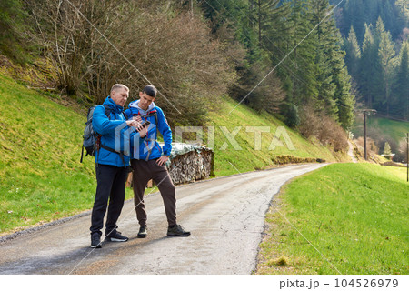 Two hikers are in the mountains in the spring nature outdoor. Hiking with backpacks. Two friends travel together in picturesque places. The man shows the way. Two men on a hiking trip in the mountains 104526979