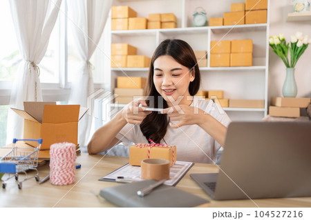 Asian Entrepreneur Working from Home, Capturing Identity Verification and Product Shipping on Mobile Phone, Working at Home: Online Store Management and Package Delivery for SMEs and Entrepreneurs. 104527216
