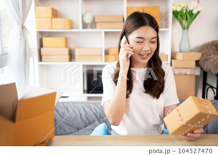 Online shopping business owner is talking on the phone with a customer to jot down the delivery address and delivery schedule, Packaging box Sell online, Work freelance. 104527470